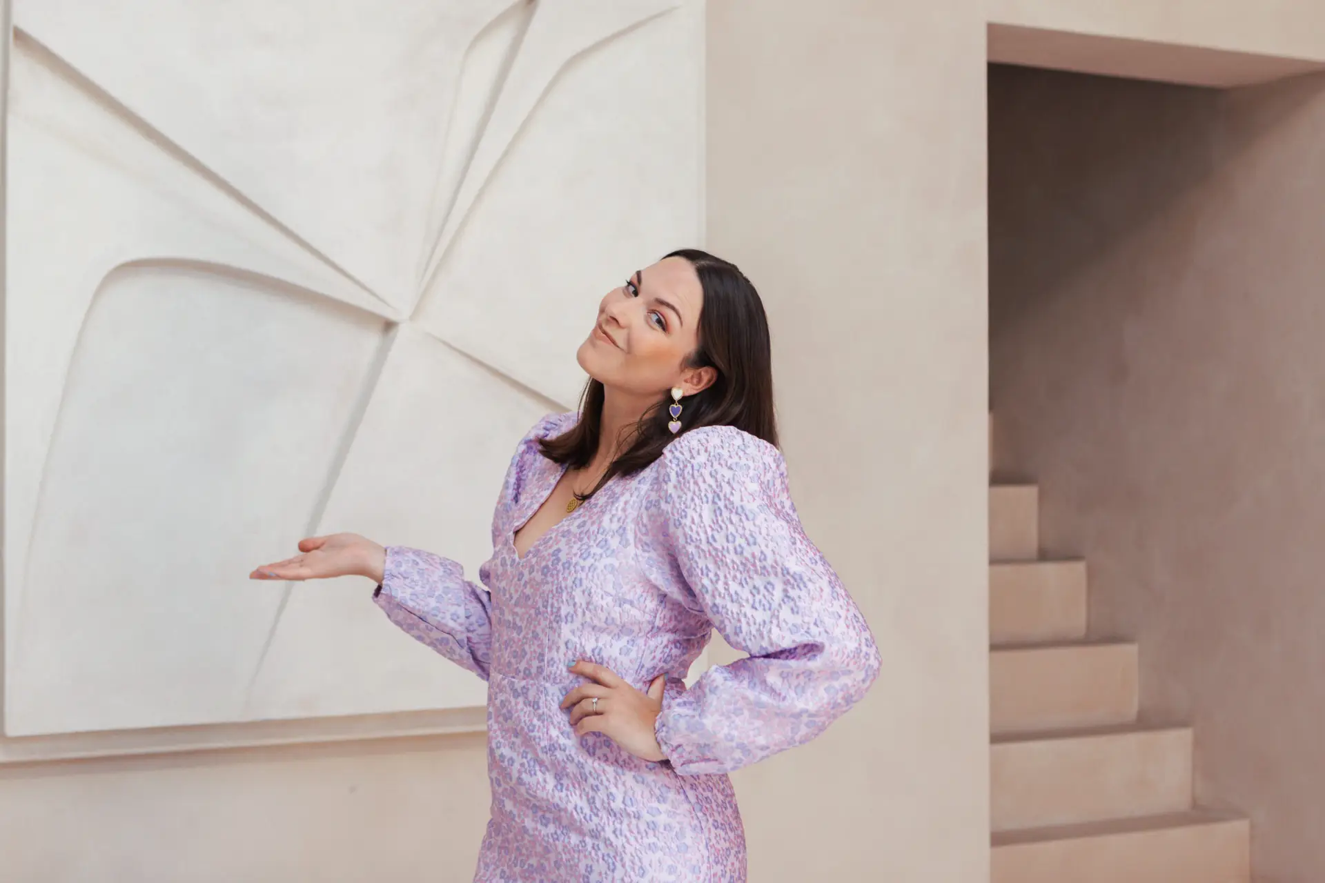 Portret van Gabrielle Lopes – Staand met opgeheven hand en open, vrolijke uitstraling Contact met Gabrielle Lopes. Gabrielle Lopes staat met opgeheven hand en glimlacht energiek – spreker en facilitator van positieve verandering