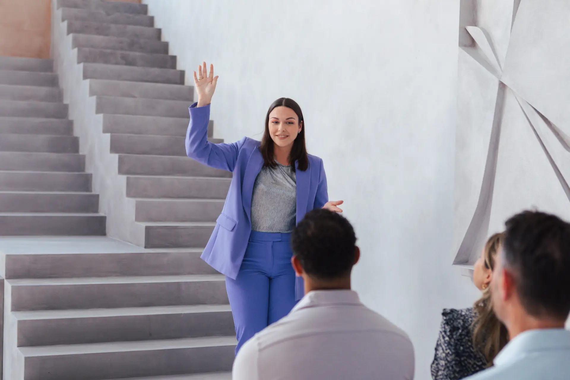 Gabrielle Lopes staat een trede hoger op een trap en spreekt vol energie tot een groep deelnemers tijdens een sessie over verandering